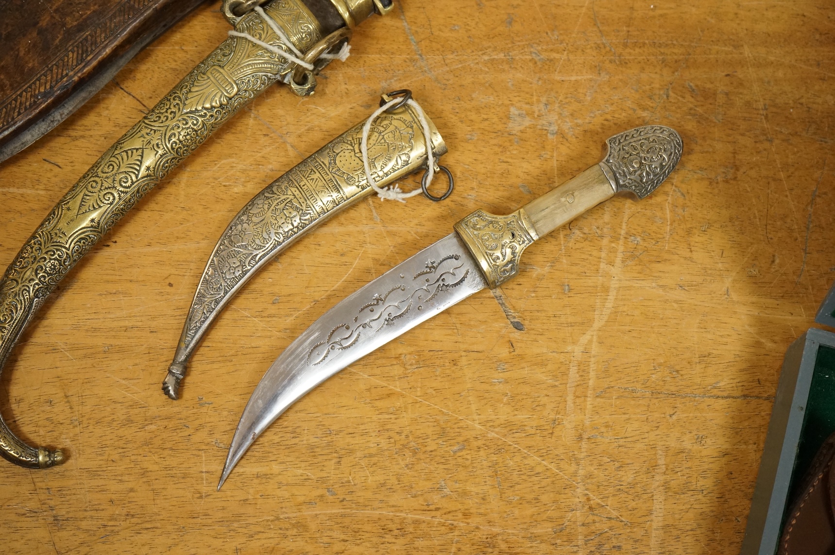 An Indian sword tulwar, the iron hilt with traces of chiselled and inlaid decoration, together with a kukri in its wooden scabbard, a Syrian jambya and a Moroccan jambiya (4)